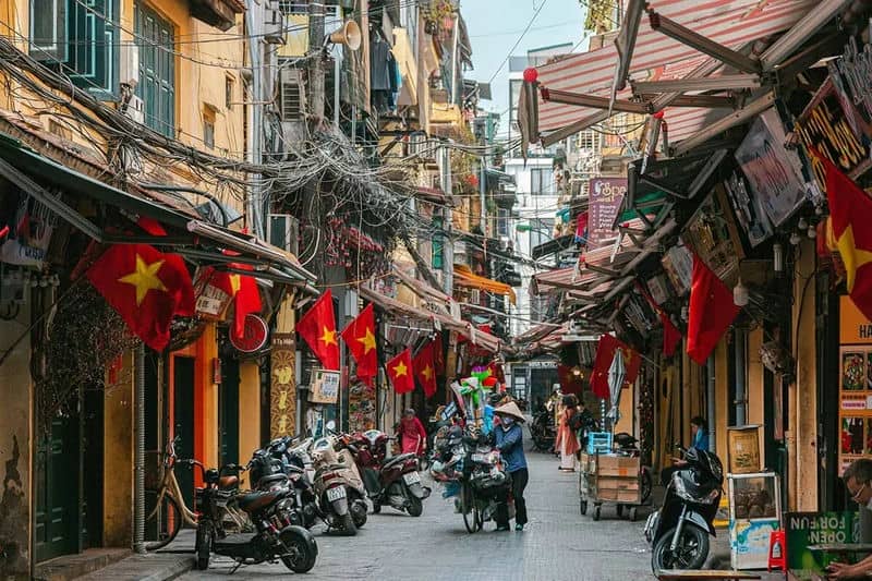 Hanoi Old Quarter street scene with red flags and motorbikes